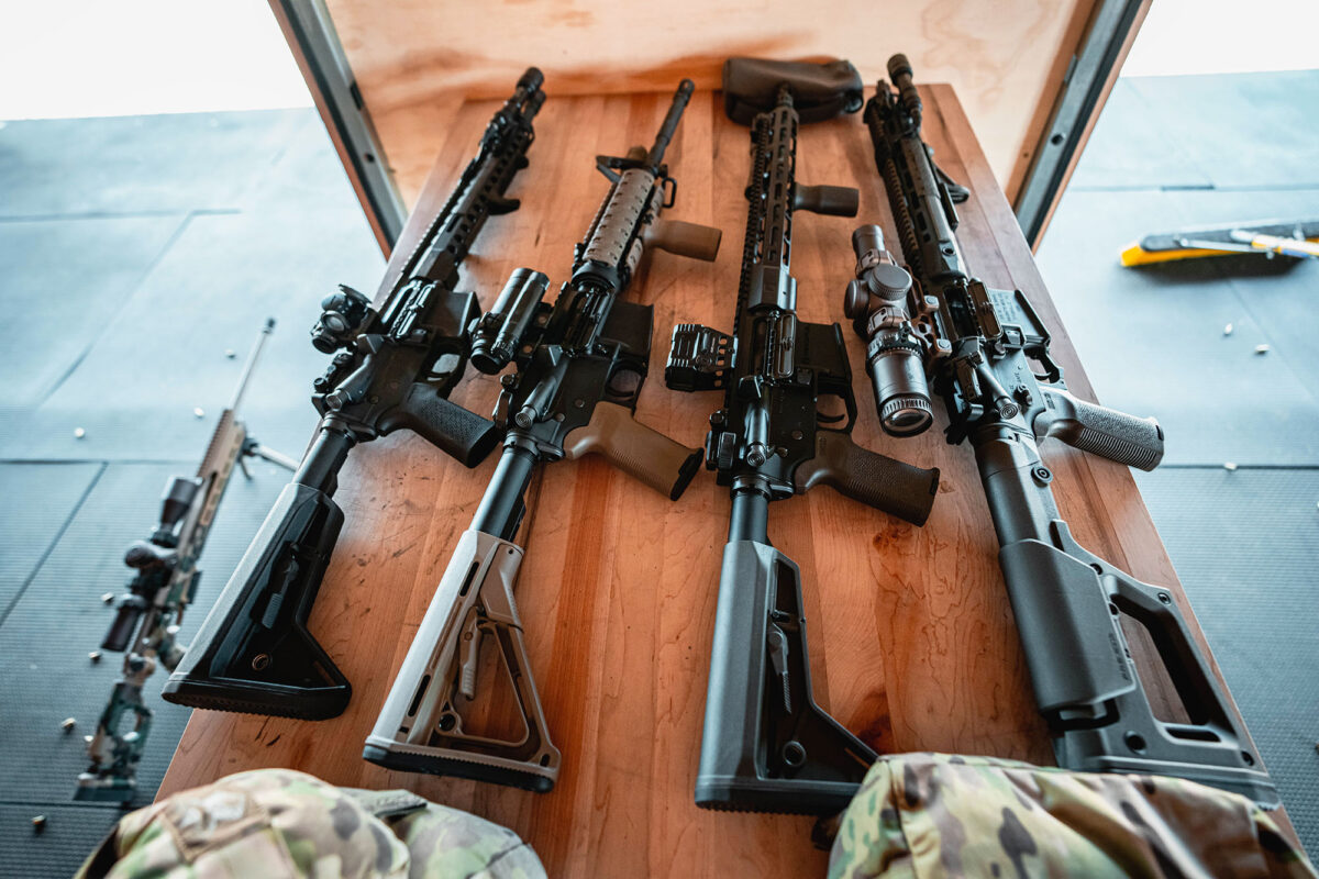 Four customized rifles on a bench.